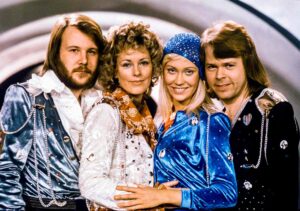 The four members of ABBA posing together, from left to right: Agnetha, Björn, Anni-Frid, and Benny, all wearing stylish 1970s outfits.